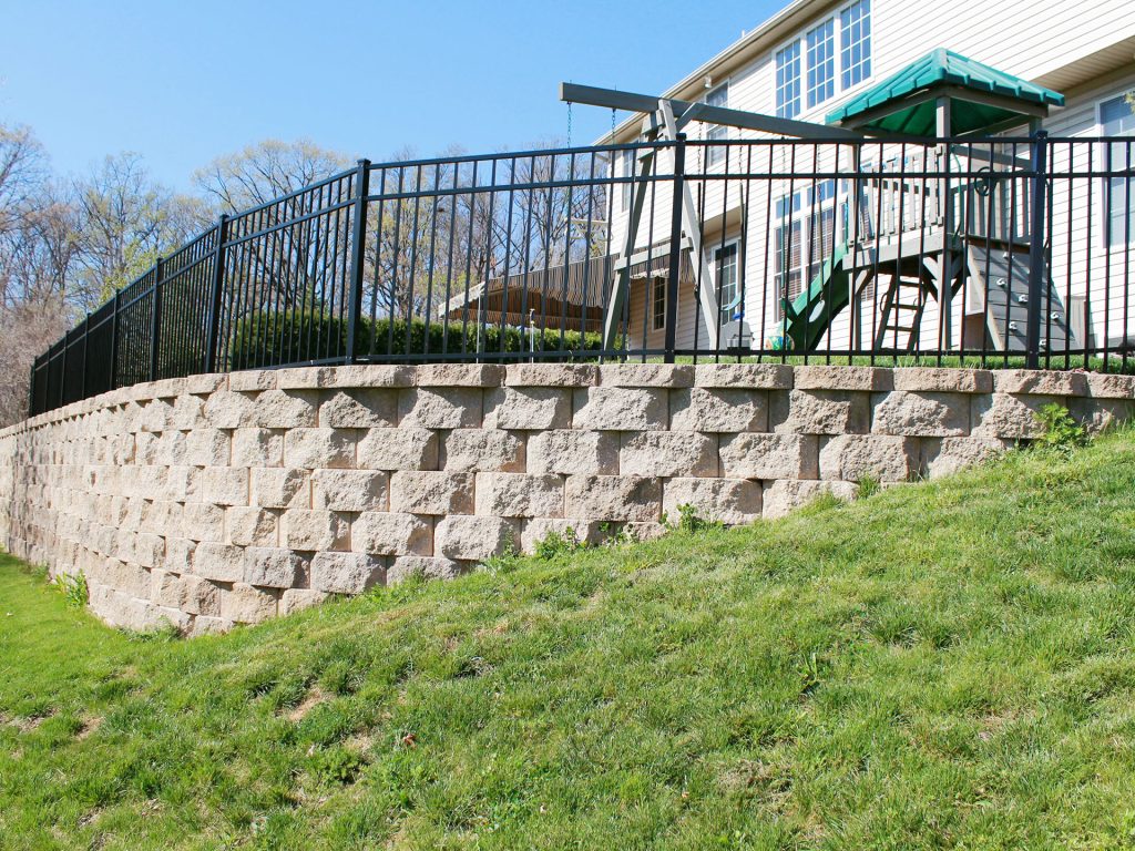 stone retaining wall of a backyard with a metal fence