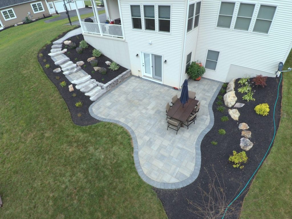 aerial view of a home's backyard with a stone patio and flower bed